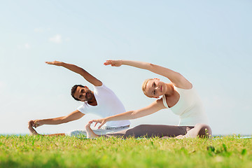 Image showing smiling couple making yoga exercises outdoors