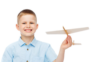 Image showing smiling little boy holding a wooden airplane model