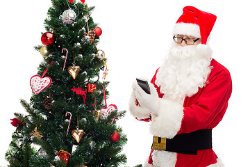 Image showing santa claus with smartphone and christmas tree