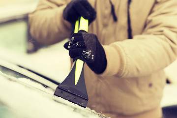 Image showing closeup of man scraping ice from car