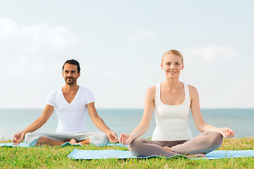 Image showing smiling couple making yoga exercises outdoors