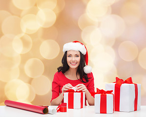 Image showing smiling woman in santa helper hats packing gifts