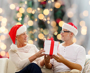 Image showing happy senior couple in santa hats with gift box