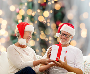 Image showing happy senior couple in santa hats with gift box