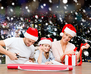 Image showing happy family in santa helper hats packing gift