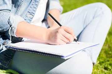 Image showing close up of girl with notebook writing in park
