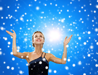 Image showing smiling woman raising hands and looking up