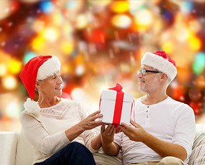 Image showing happy senior couple in santa hats with gift box