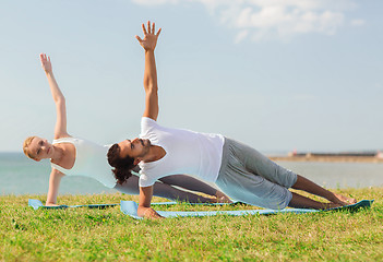 Image showing smiling couple making yoga exercises outdoors