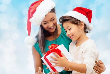 Image showing happy mother and girl in santa hats with gift box