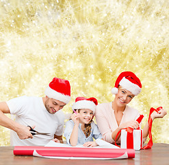 Image showing happy family in santa helper hats packing gift