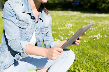 Image showing close up of girl with tablet pc sitting on grass