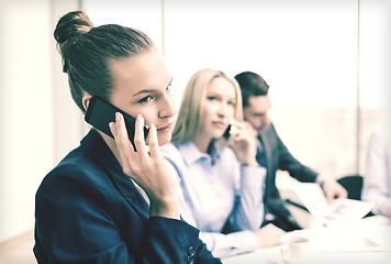 Image showing smiling business team with smartphones in office