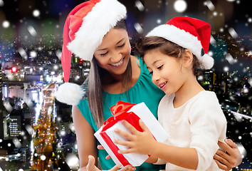 Image showing happy mother and girl in santa hats with gift box