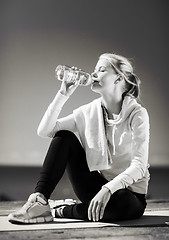 Image showing woman drinking water after doing sports outdoors