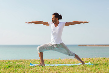 Image showing smiling man making yoga exercises outdoors