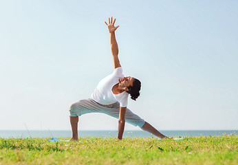 Image showing smiling man making yoga exercises outdoors