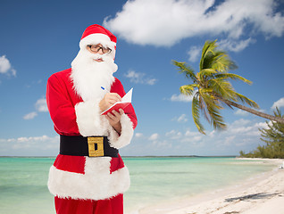 Image showing man in costume of santa claus with notepad