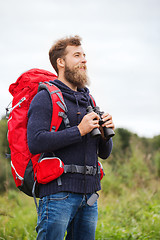 Image showing smiling man with backpack and binocular outdoors