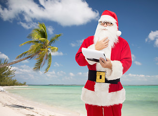 Image showing man in costume of santa claus with notepad