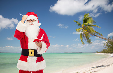 Image showing man in costume of santa claus with notepad