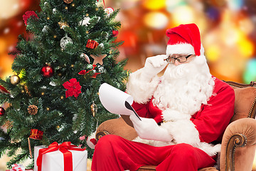 Image showing man in costume of santa claus with notepad