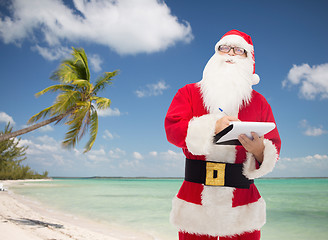 Image showing man in costume of santa claus with notepad