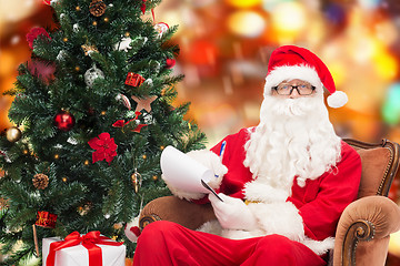 Image showing man in costume of santa claus with notepad