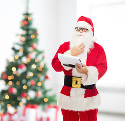 Image showing man in costume of santa claus with notepad