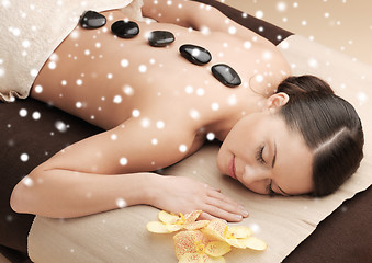 Image showing woman in spa salon with hot stones