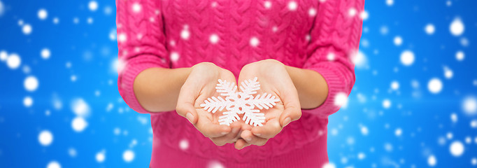 Image showing close up of woman in sweater holding snowflake