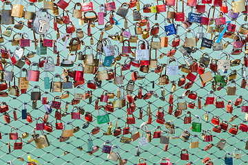 Image showing Padlocks hanging on the bridge over the river