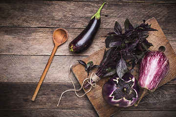 Image showing Aubergines and basil on and wooden table