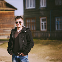 Image showing Young Handsome Man Staying Near Old Wooden House In Autumn Or Sp