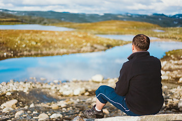 Image showing Man Sitting On Stone In Norwegian Mountains