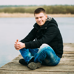 Image showing Young Handsome Man Sitting On Wooden Pier, Relaxing,  Thinking, 