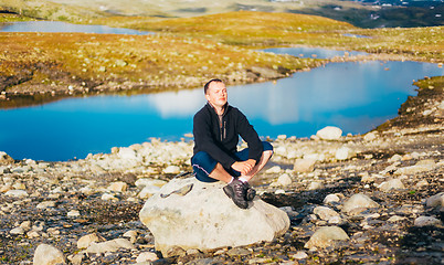 Image showing Man Sitting On Stone In Norwegian Mountains