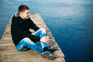 Image showing Young Handsome Man Sitting On Wooden Pier, Relaxing,  Thinking, 