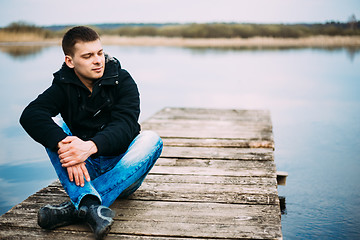 Image showing Young Handsome Man Sitting On Wooden Pier, Relaxing,  Thinking, 