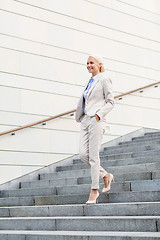 Image showing young smiling businesswoman walking down stairs