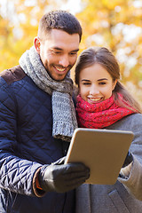 Image showing smiling couple with tablet pc in autumn park