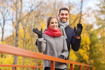 Image showing smiling couple hugging on bridge in autumn park