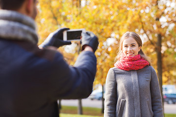 Image showing smiling couple with smartphone in autumn park