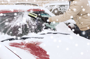 Image showing closeup of man cleaning snow from car