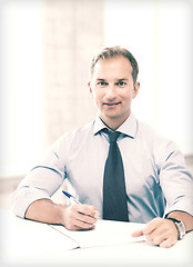 Image showing handsome businessman writing in notebook