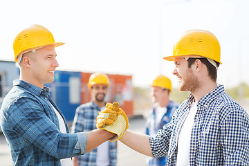 Image showing group of smiling builders in hardhats outdoors