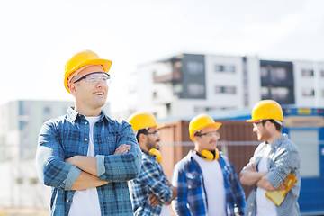 Image showing group of smiling builders in hardhats outdoors