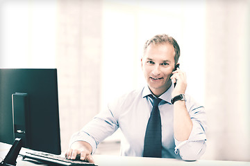 Image showing smiling businessman with smartphone in office