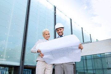 Image showing smiling businessmen with blueprint and helmets