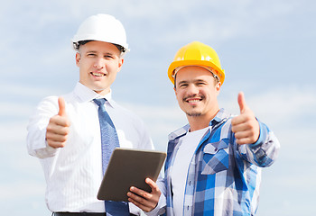 Image showing smiling builders in hardhats with tablet pc